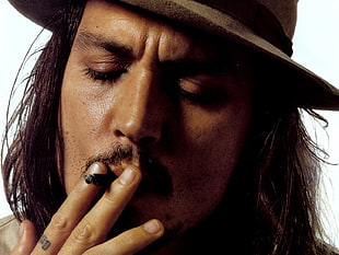 Johnny Depp wearing brown hat and smoking lighted cigarette
