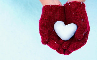 person in red knitted gloves showing heart