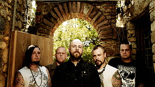 photo of a boy band under gray and brown concrete arch
