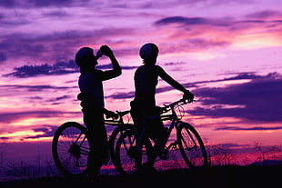 silhouette of two boy's riding mountain bike one drinking bottle during daytime