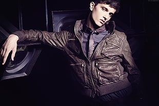 man in brown leather jacket leaning on studio light