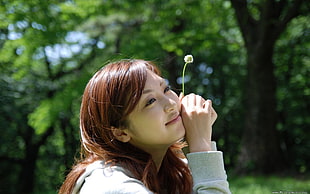 woman holding white flower smiling at daytime