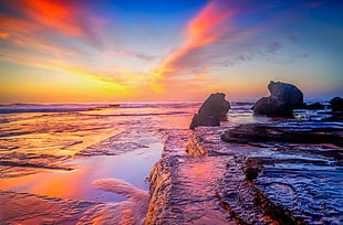 panaroma photo of body of water near rock formation under golden hour HD wallpaper