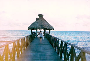 woman walking on wooden dock on body of water HD wallpaper
