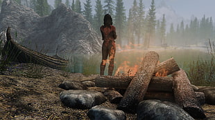 flaming woman standing near body of water and burning woods