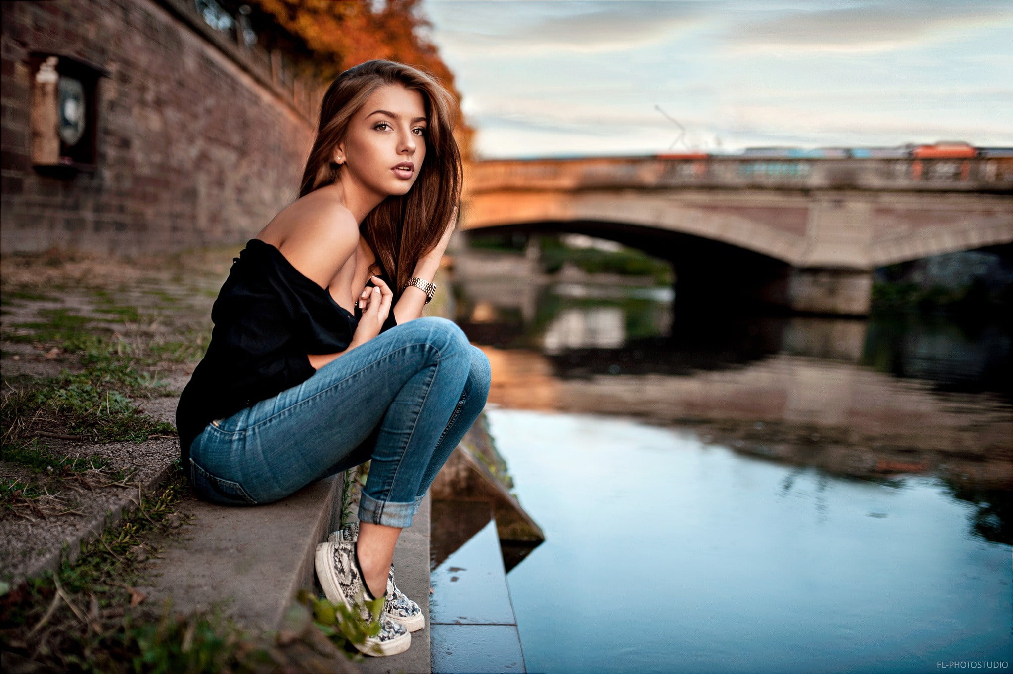 Woman wearing black off-shoulder blouse sits near lake during daytime ...