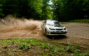 white and black Subaru Impreza rally car drifting soil pavement