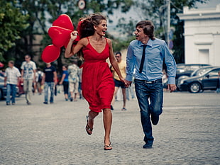 woman carrying balloon running holding hands with man