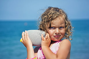 closeup photography of girl holding gray rock during daytime