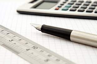 close up of fountain pen on white graphing paper near calculator and ruler