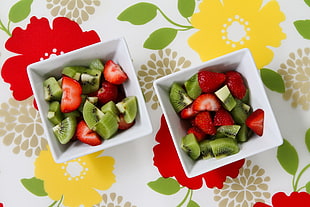 two bowls of sliced strawberries and kiwi fruits
