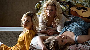 three woman taking a photo shoot on bed
