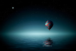 hot air balloon above the ocean during nighttime HD wallpaper