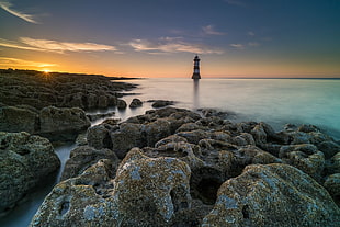 rock formation beside sea water near lighthouse, penmon HD wallpaper