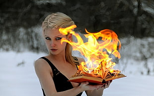 blonde woman holding book with flames