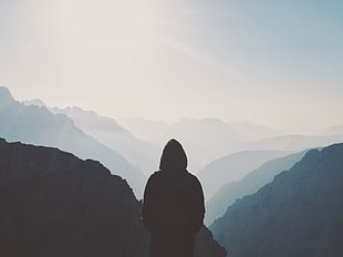 person wearing black hoodie overlooking mountain range