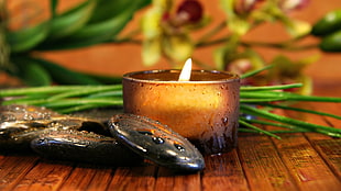 lighted brown candle votive beside green vegetables