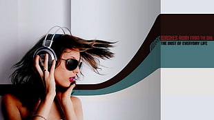 woman wears black and gray wireless headphones and black sunglasses stands beside a wall