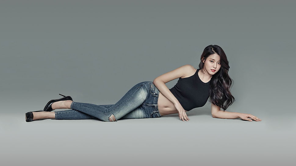 woman in black tank top and blue jeans lying on gray surface HD wallpaper