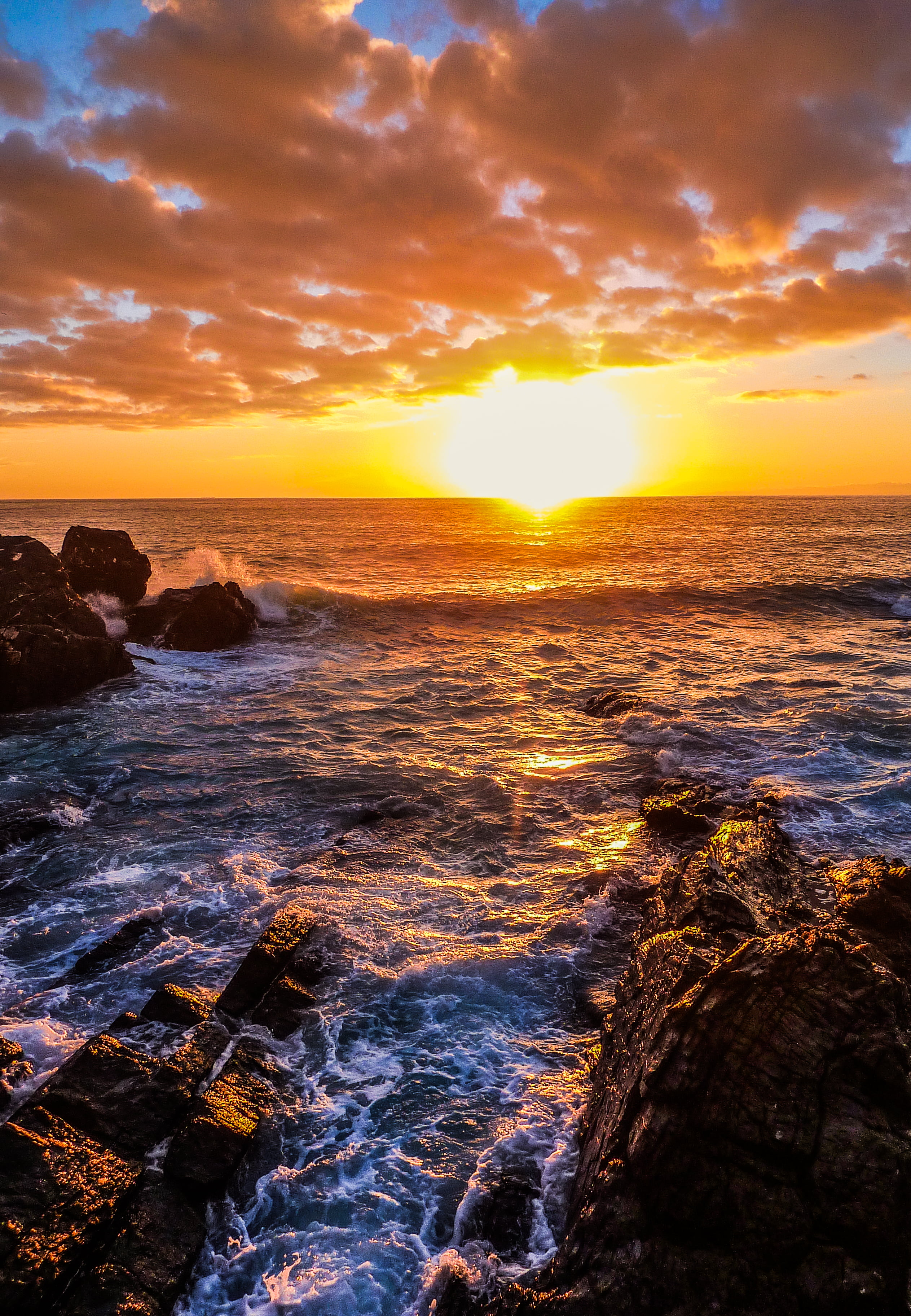 scenery of sea and brown rocks during sunset