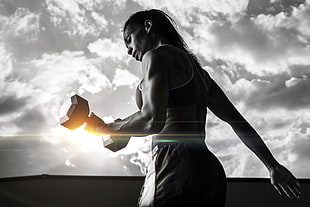 Grayscale photo of woman exercising using dumbbell