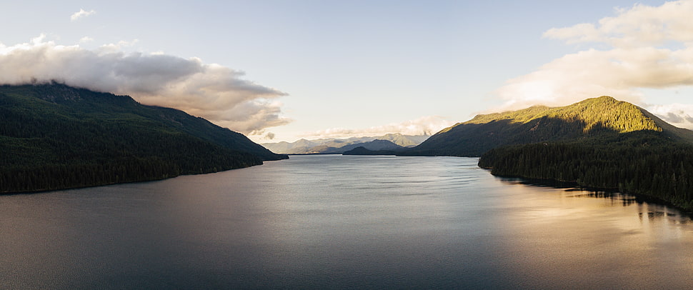 body of water near mountains at daytime HD wallpaper