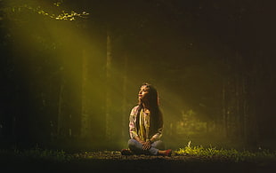 photo of woman siting on forest while facing sunlight