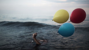 three red, yellow, and teal balloons, hands, balloon, water, sea