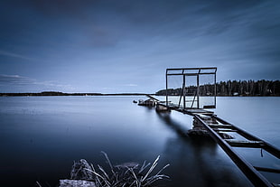 gray metal dock over still body of water