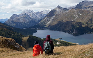 man and woman wearing hoodie jacket seating on mountain