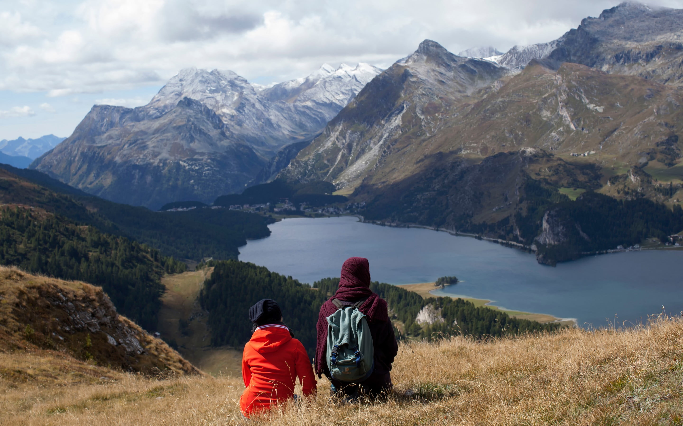 man and woman wearing hoodie jacket seating on mountain