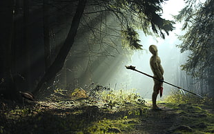 person holding spear standing under tree during daytime