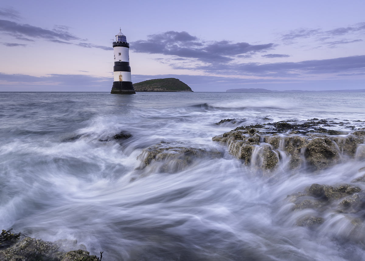 photo of white and black lighthouse in middle of body of water, penmon, anglesey