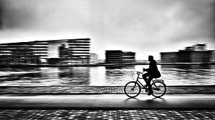 grayscale photo of man driving bicycle