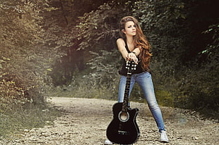 woman holding black acoustic guitar