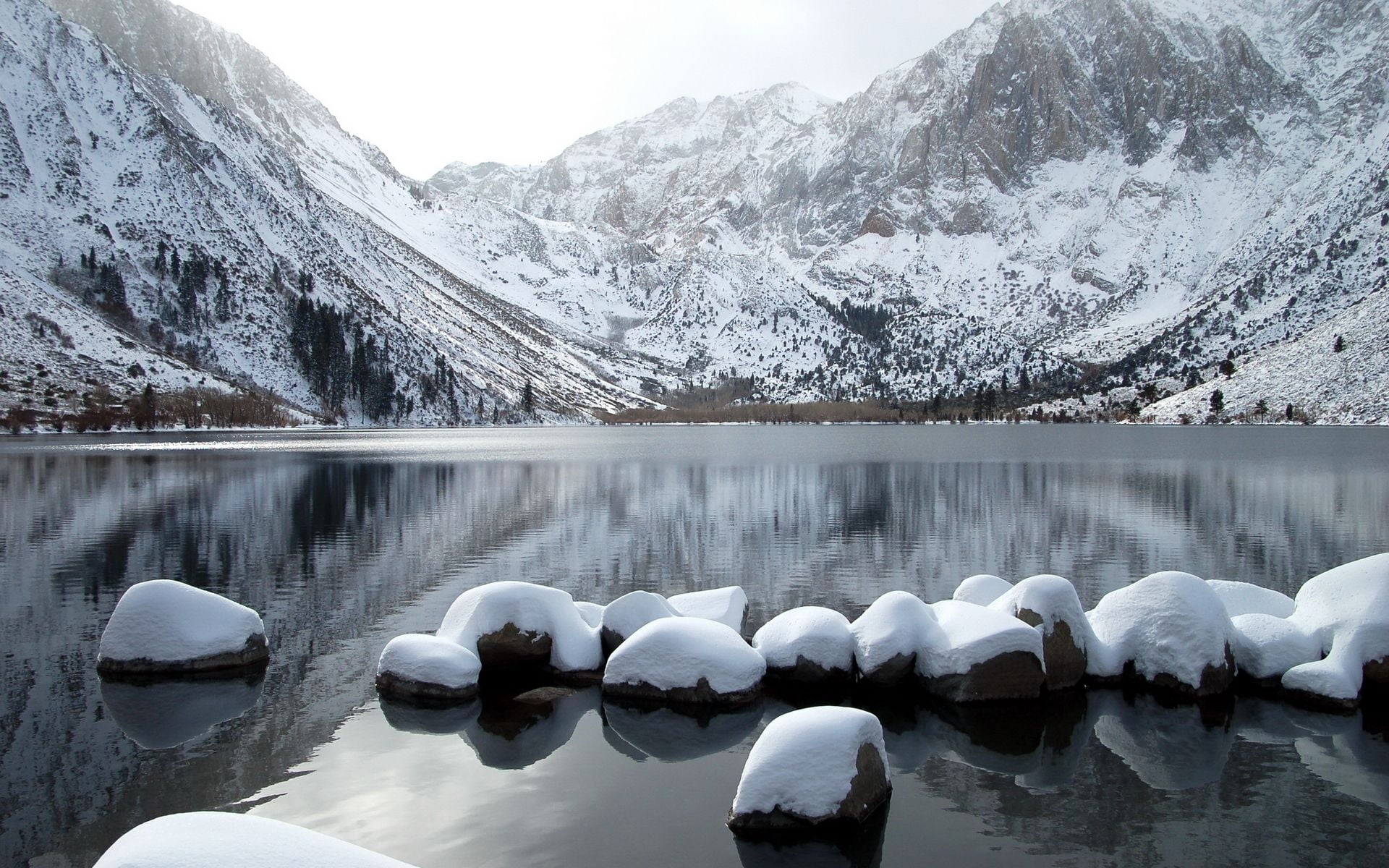 snow covered mountain and rocks surrounded by body of water
