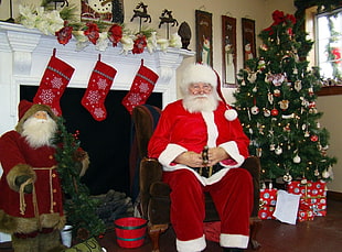 man in Santa Claus costume sitting in front of fireplace
