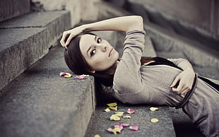 woman wearing gray cardigan lying down at gray concrete stairs