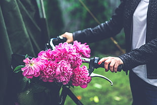 person holding beach cruiser handle bar with bouquet of flowers
