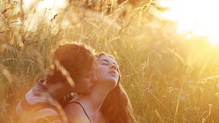 man and woman kissing on green grass field