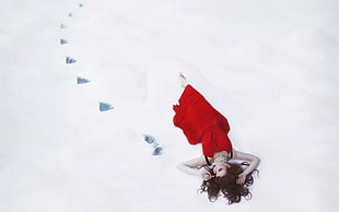 woman wearing red dress lying snow