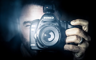 man holding black Canon digital SLR camera