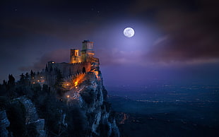 brown castle in front of sea during full moon display wallpaper