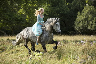 woman in blue dress riding on gray horse