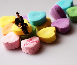 close up photo of man wearing hat figurine on multi-color heart-shaped decors