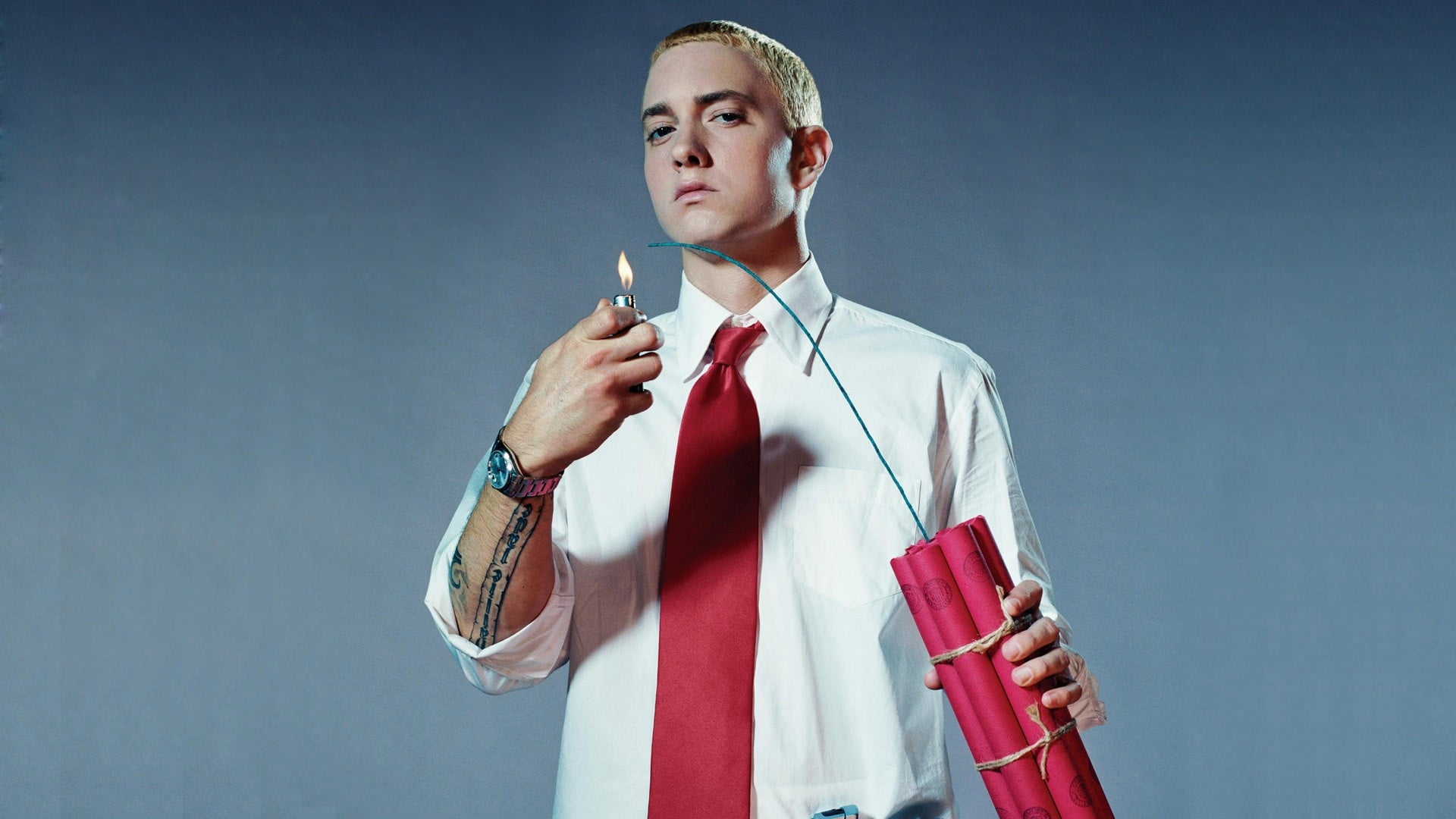 Marshall Mathers in white dress shirt and red necktie holding red bomb
