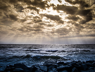 photo of sky with sunburst over body of water HD wallpaper