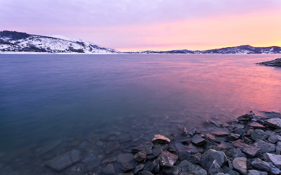 pebbles near seashore near snow-filled mountain HD wallpaper