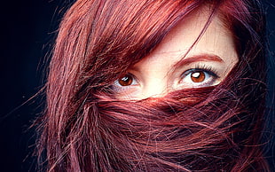 women's face covered by red hair