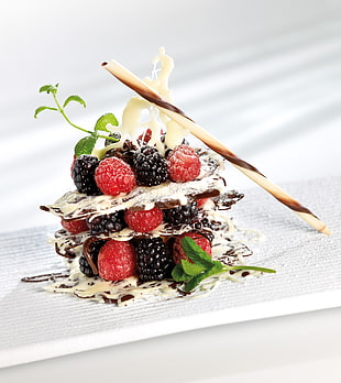 blue and red berries with white coated cream on white surface